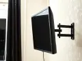 Czarny uchwyt telewizyjny na ścianie, z kablem TV. Idealna wysokość dla komfortowego oglądania.