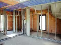 Konstrukcja pod scianke dzialowa z plyty kartonowo gipsowej, widoczne profile metalowe, instalacje elektryczne i hydrauliczne, sciany z cegly.