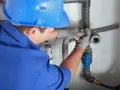 Instalator montuje odpowietrzenie kanału sanitarnego w domu parterowym.