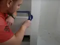 Mężczyzna okleja taśmą krawędzie płytek, przygotowując się do aplikacji fugi epoksydowej. Unikanie błędów to klucz do sukcesu.