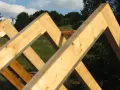 Drewniane krokwie tworzą konstrukcję dachu, ich łączenie w szczycie jest solidne i gotowe na kolejne etapy budowy.