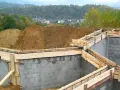 Budowa fundamentów zbrojonych, przygotowanie do wylania betonu. W tle widok na osiedle. To etap po uzyskaniu pozwolenia na budowę, zgodny z warunkami zabudowy.