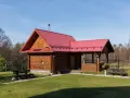 Drewniany domek letniskowy z czerwonym dachem, idealny na wypoczynek. Marzysz o takim? Sprawdź dofinansowanie na domek letniskowy!