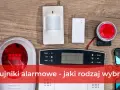 System alarmowy satel. na drewnianym tle: czujnik ruchu, panel sterowania, sygnalizator i piloty.