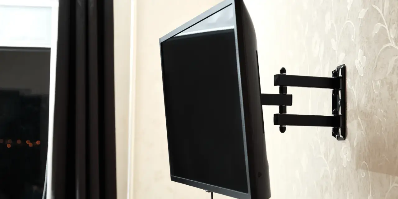 Czarny uchwyt telewizyjny na ścianie, z kablem TV. Idealna wysokość dla komfortowego oglądania.