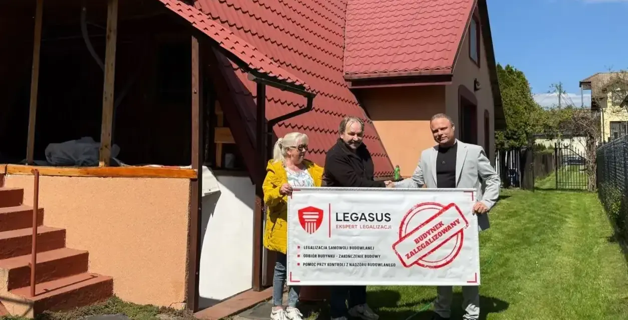Trzy osoby trzymają baner "Budynek zalegalizowany", symbolizujący jak zrobić odbiór domu po 20 latach.