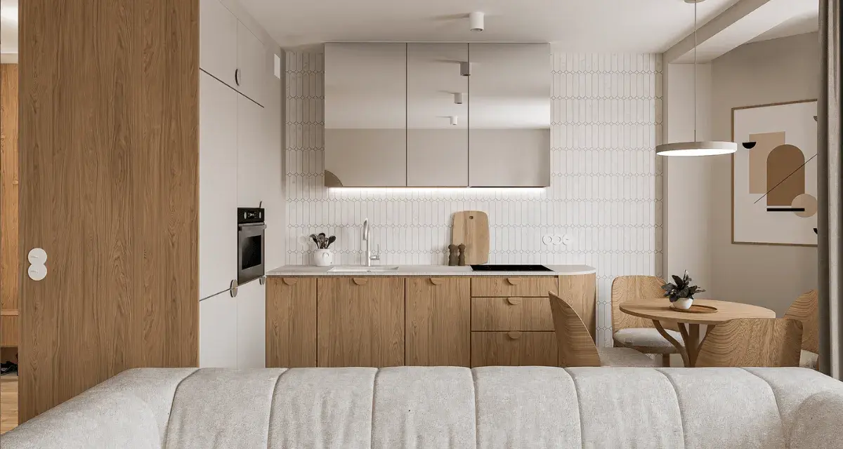 Nowoczesny salon z aneksem kuchennym. Jasne drewno, lustrzane fronty szafek i minimalistyczny design tworzą przytulną atmosferę.