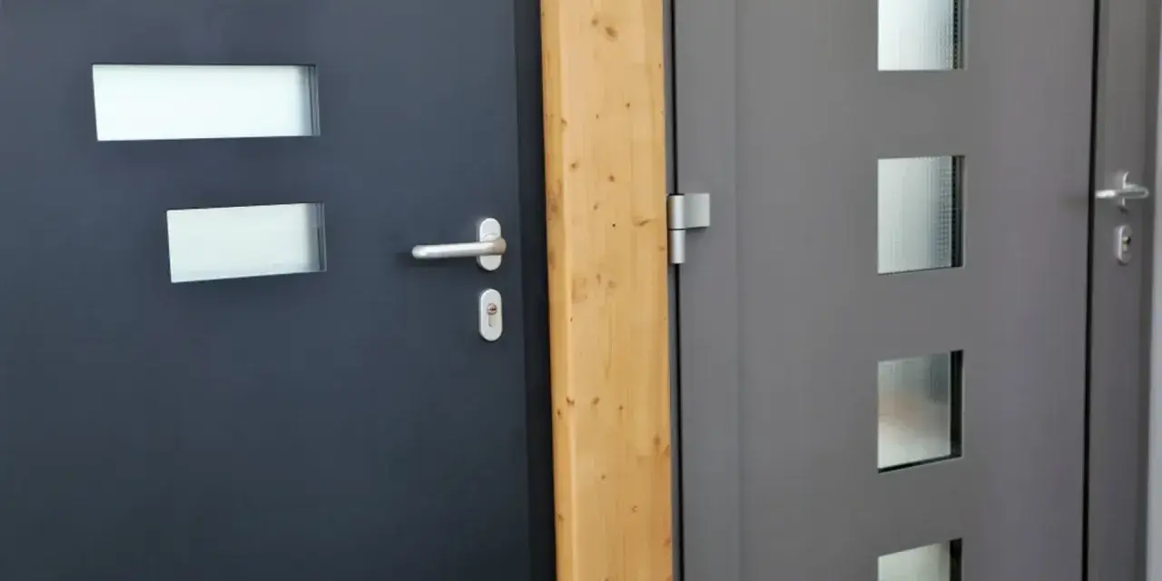 Dwie nowoczesne drzwi wejściowe, ciemnoszare i szare, z przeszkleniami. Dowiedz się, jak uszczelnić drzwi wejściowe, by chronić dom przed zimnem.