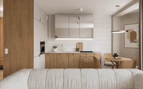 Nowoczesny salon z aneksem kuchennym. Jasne drewno, lustrzane fronty szafek i minimalistyczny design tworzą przytulną atmosferę.