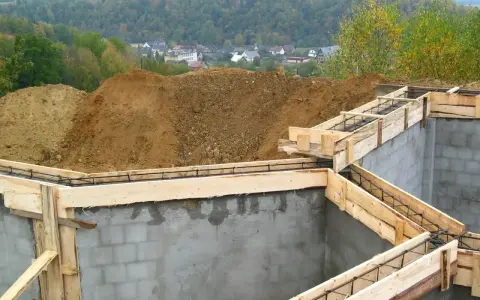 Budowa fundamentów zbrojonych, przygotowanie do wylania betonu. W tle widok na osiedle. To etap po uzyskaniu pozwolenia na budowę, zgodny z warunkami zabudowy.