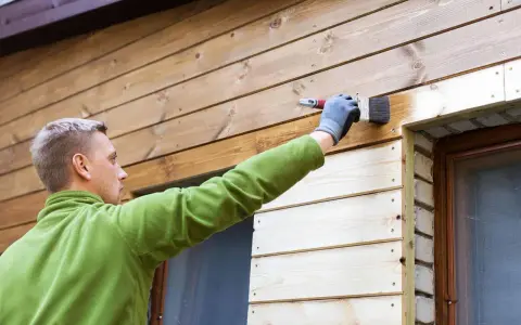 Mężczyzna maluje deskę elewacyjną, tworząc piękne aranżacje.