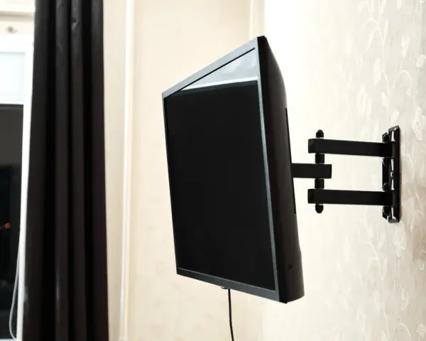 Czarny uchwyt telewizyjny na ścianie, z kablem TV. Idealna wysokość dla komfortowego oglądania.