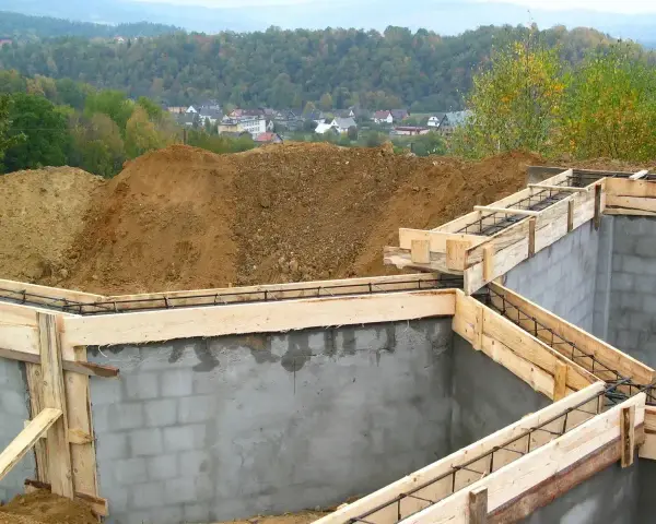 Budowa fundamentów zbrojonych, przygotowanie do wylania betonu. W tle widok na osiedle. To etap po uzyskaniu pozwolenia na budowę, zgodny z warunkami zabudowy.