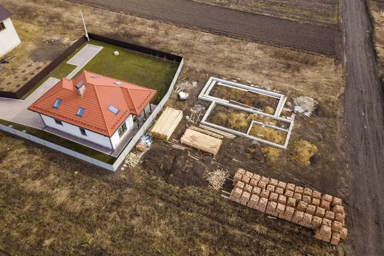 Budowa zabudowy zagrodowej w toku: fundamenty, drewno i cegły czekają na budowniczych.