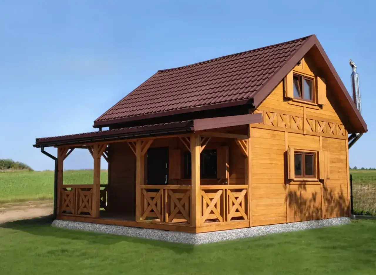 Drewniany domek letniskowy z werandą, idealny na wypoczynek. Marzysz o takim miejscu? Sprawdź, jak uzyskać dofinansowanie na domek letniskowy.