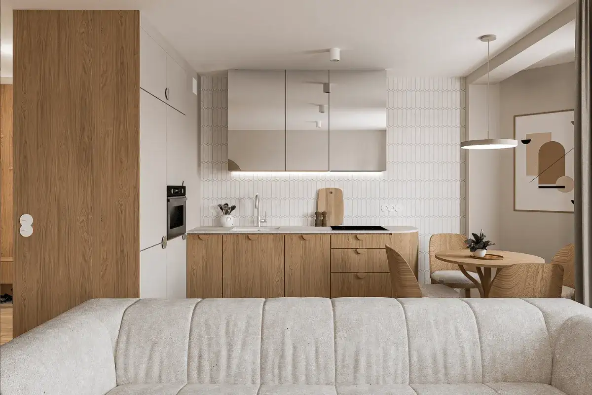 Nowoczesny salon z aneksem kuchennym. Jasne drewno, lustrzane fronty szafek i minimalistyczne detale tworzą przytulną atmosferę.