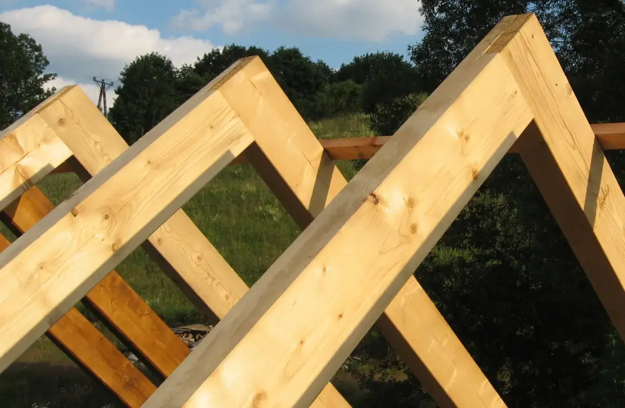 Drewniane krokwie tworzą solidne łączenie w szczycie dachu, gotowe na pokrycie.
